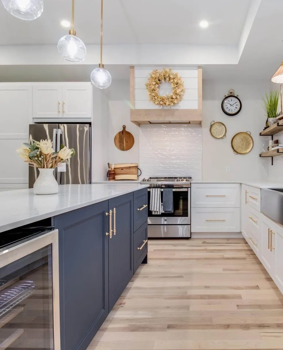 White kitchen with navy island and brass pendant lights